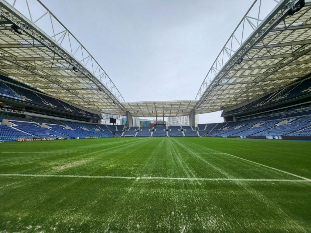 Panoramic view of an empty soccer stadium with vibrant green field and high roof structure.