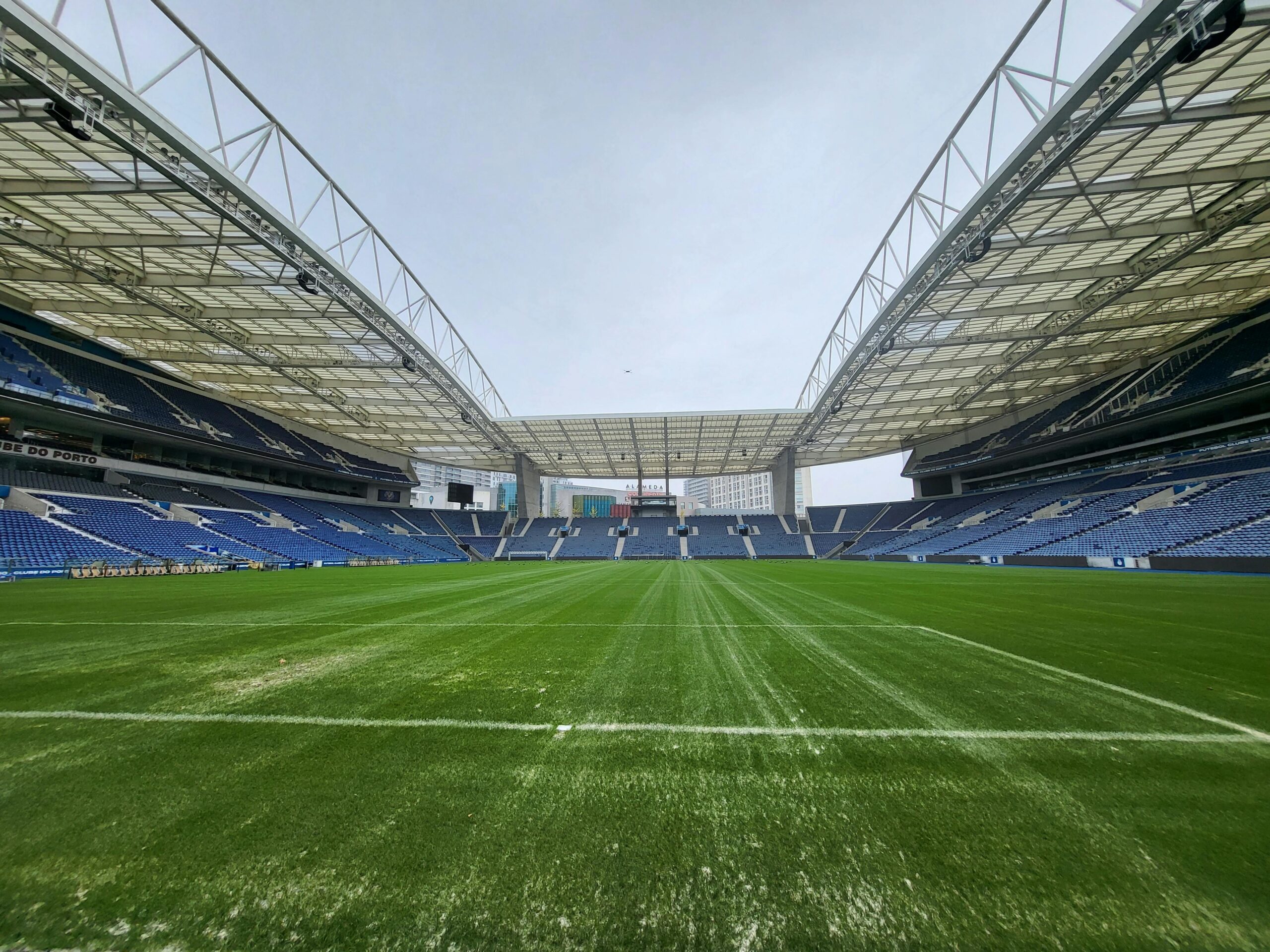 Panoramic view of an empty soccer stadium with vibrant green field and high roof structure.